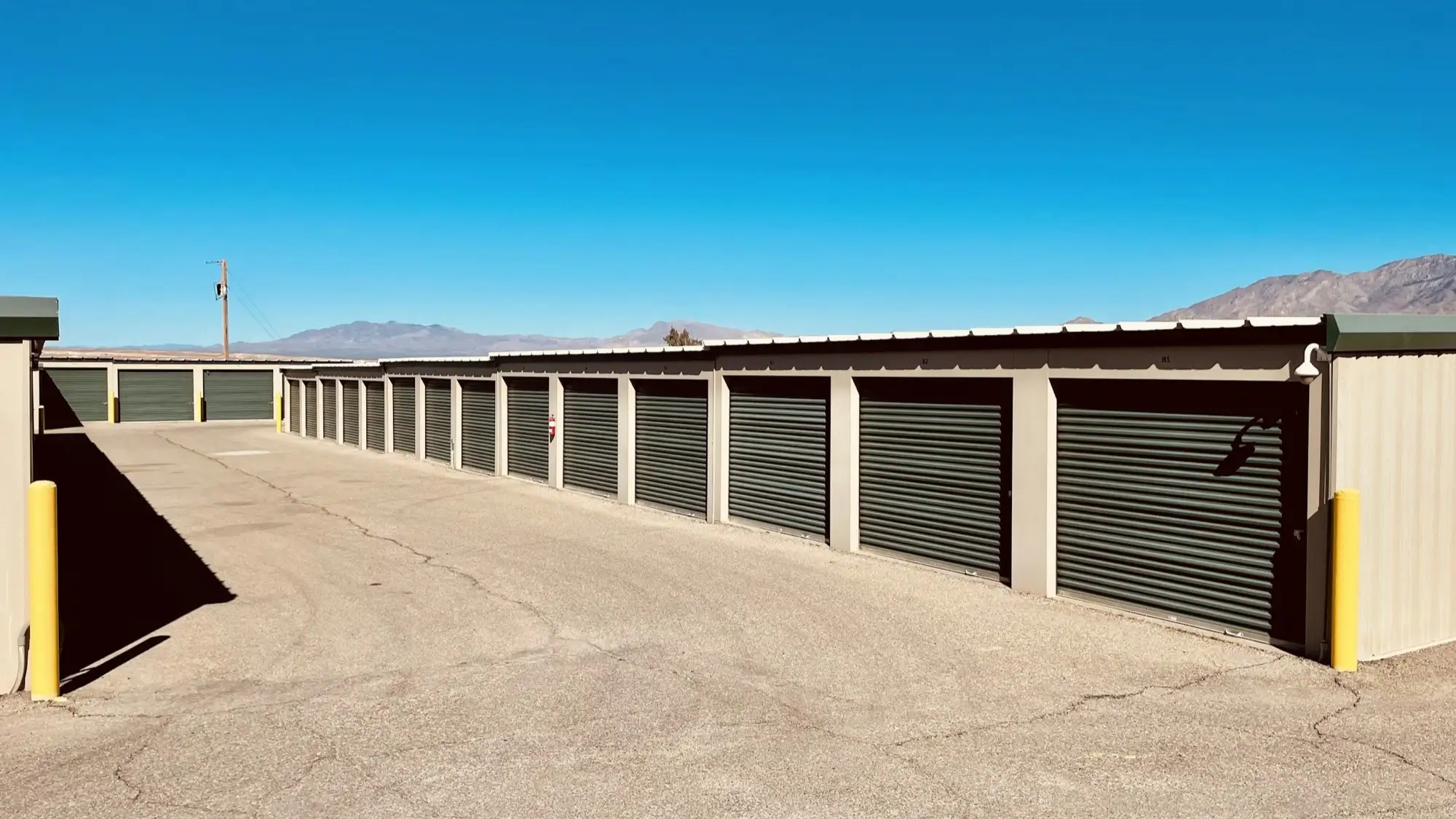Self storage facility with green drive up doors and mountains under a clear sky
