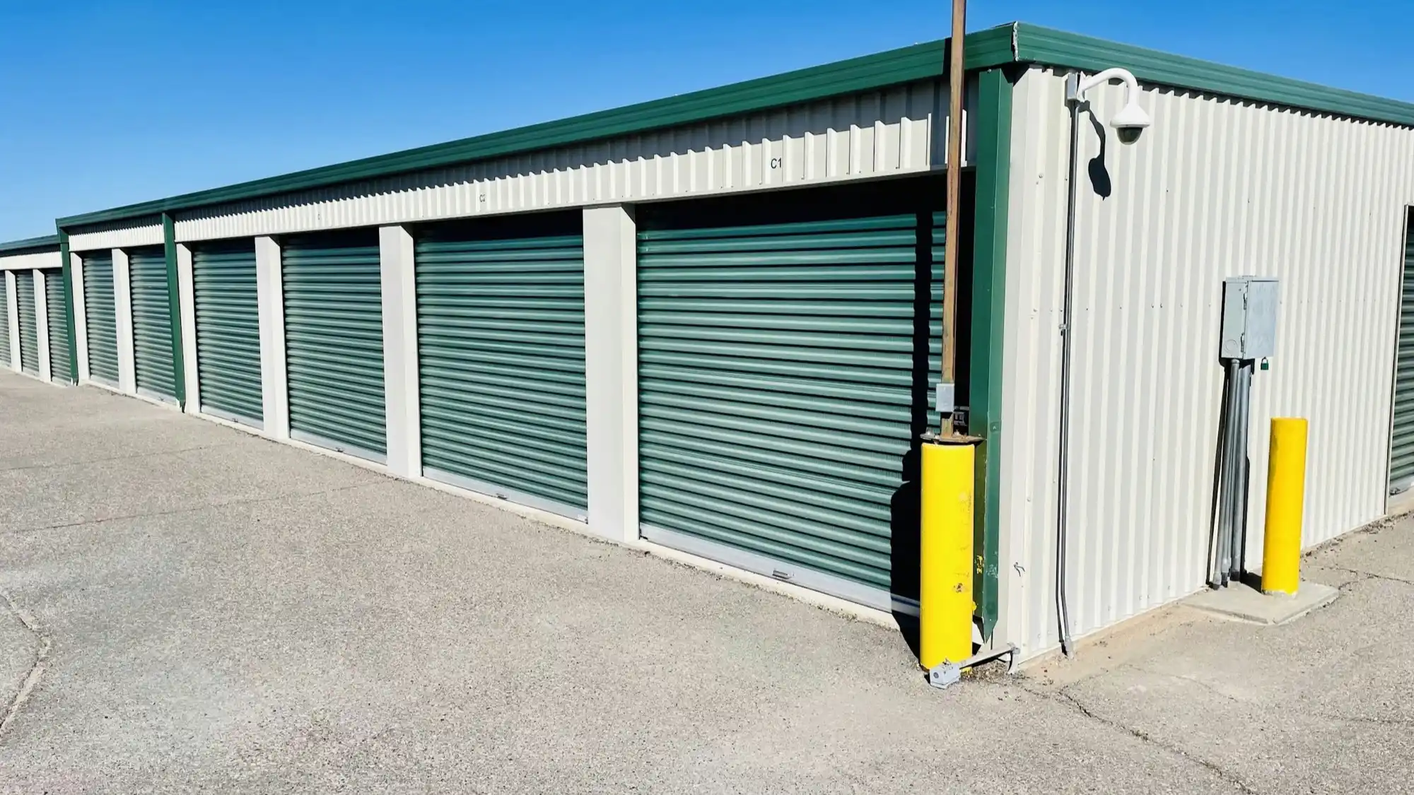 Rows of green door self storage units at a bright clean facility